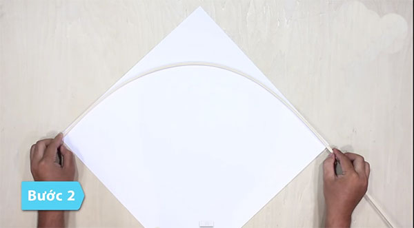 Đặt cánh cung này lên hình vuông giấy sao cho dây cước chạy theo 1 đường chéo cua hình vuông.